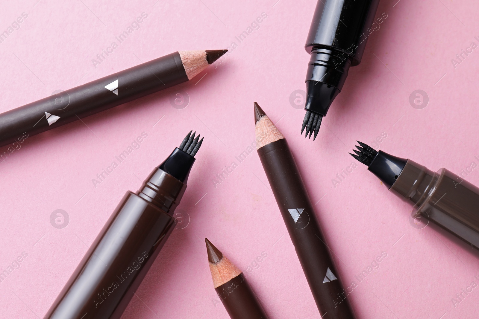 Different eyebrow pencils on pink background, closeup Photo of Different eyebrow pencils on pink background, closeup