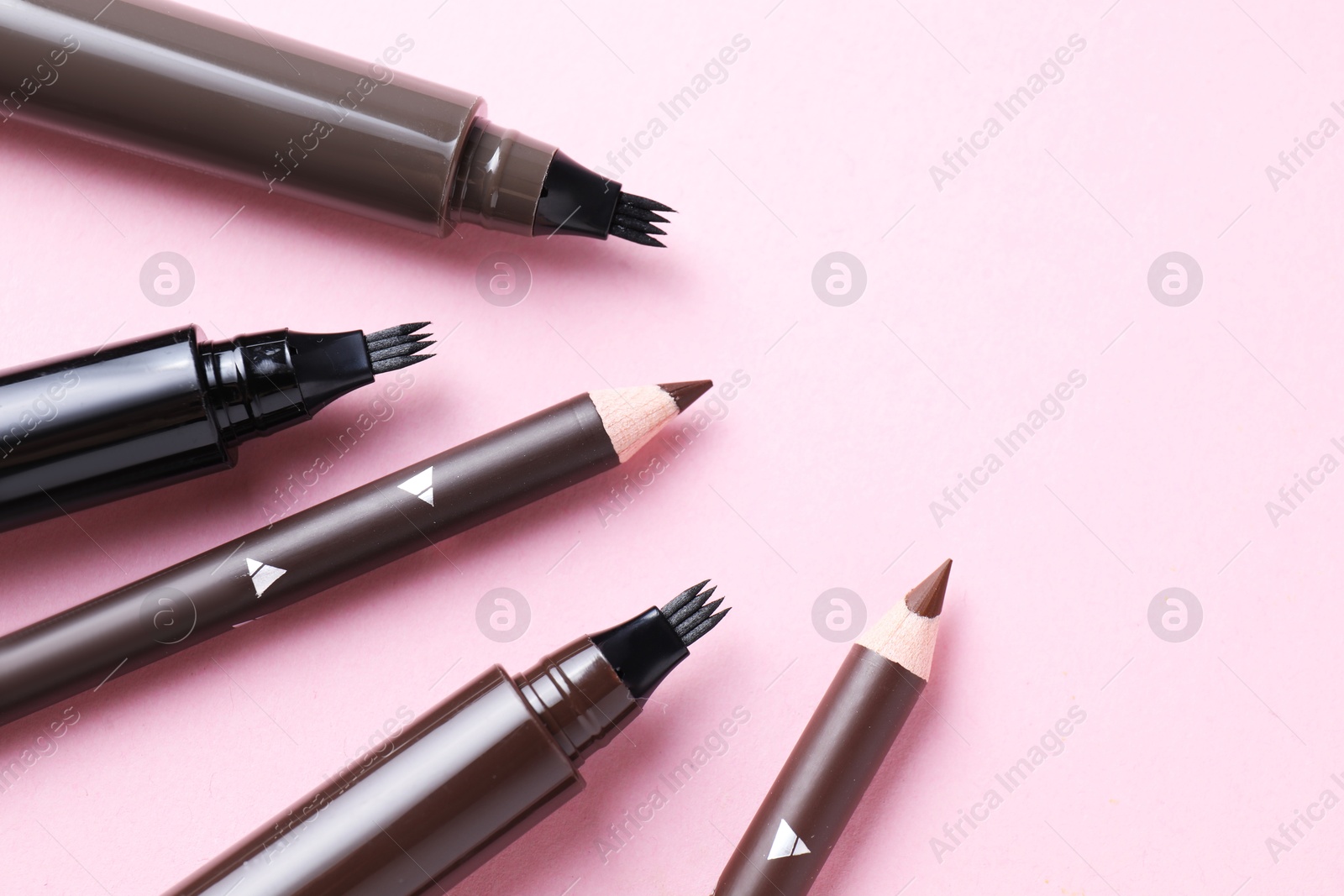 Different eyebrow pencils on pink background, closeup. Space for text Photo of Different eyebrow pencils on pink background, closeup. Space for text