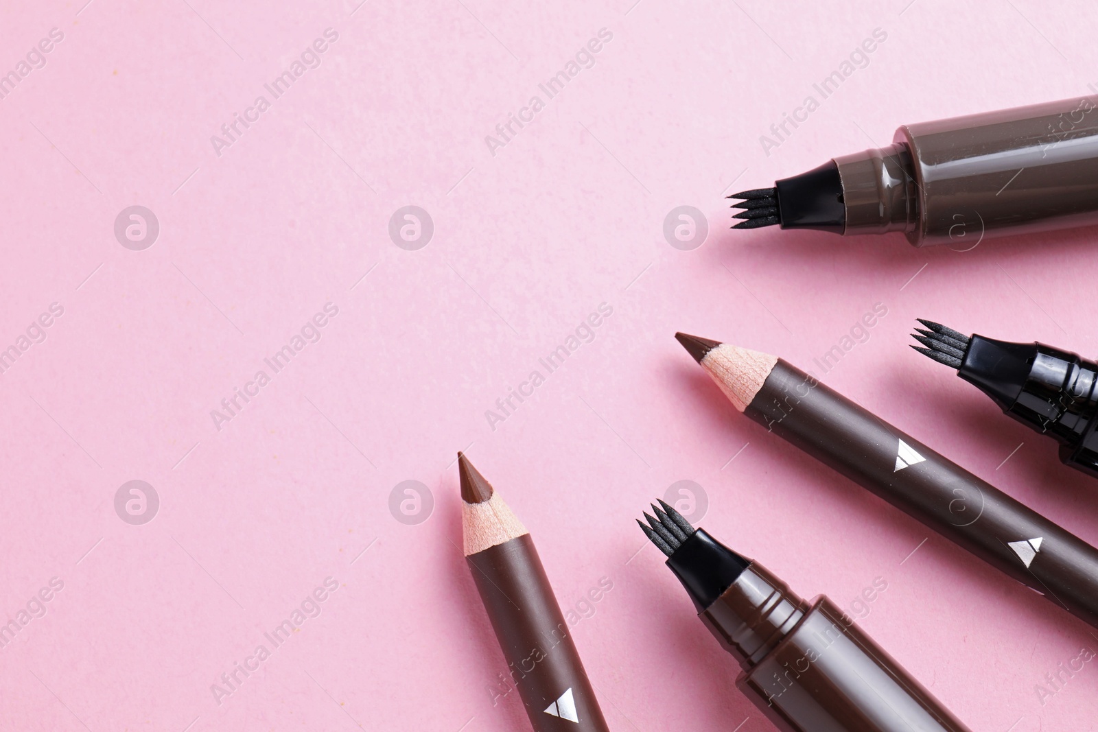 Different eyebrow pencils on pink background, closeup. Space for text Photo of Different eyebrow pencils on pink background, closeup. Space for text
