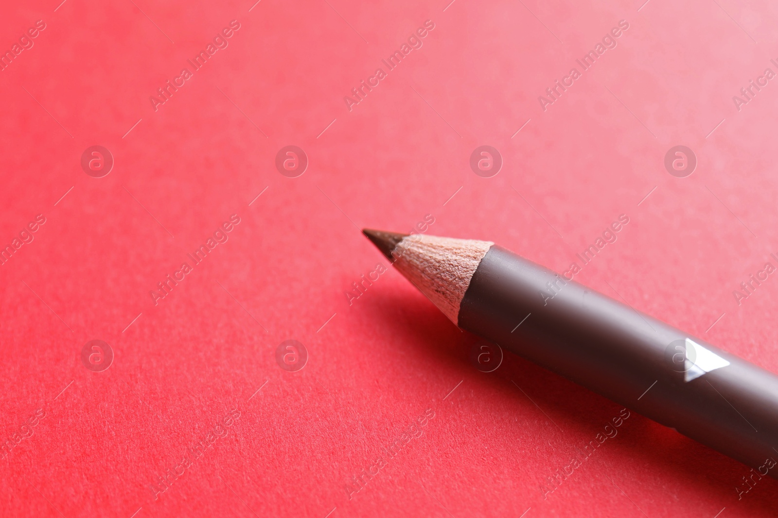 One eyebrow pencil on red background, closeup. Space for text Photo of One eyebrow pencil on red background, closeup. Space for text