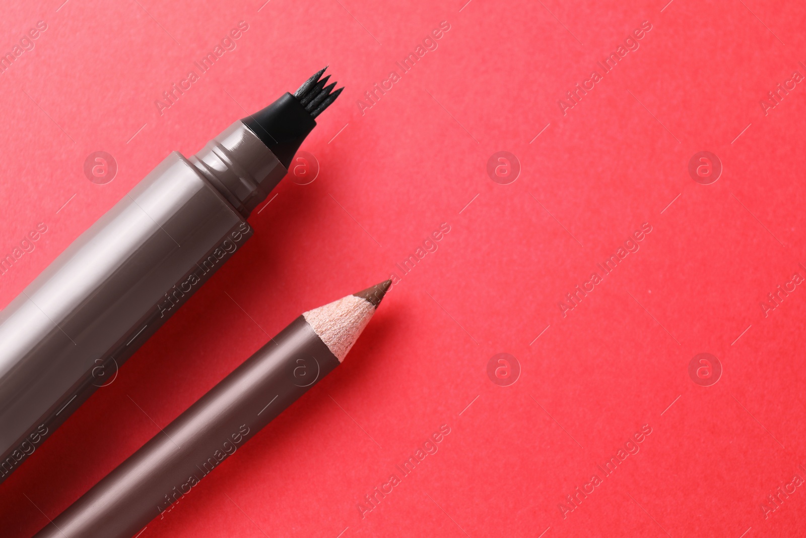 Different eyebrow pencils on red background, closeup. Space for text Photo of Different eyebrow pencils on red background, closeup. Space for text