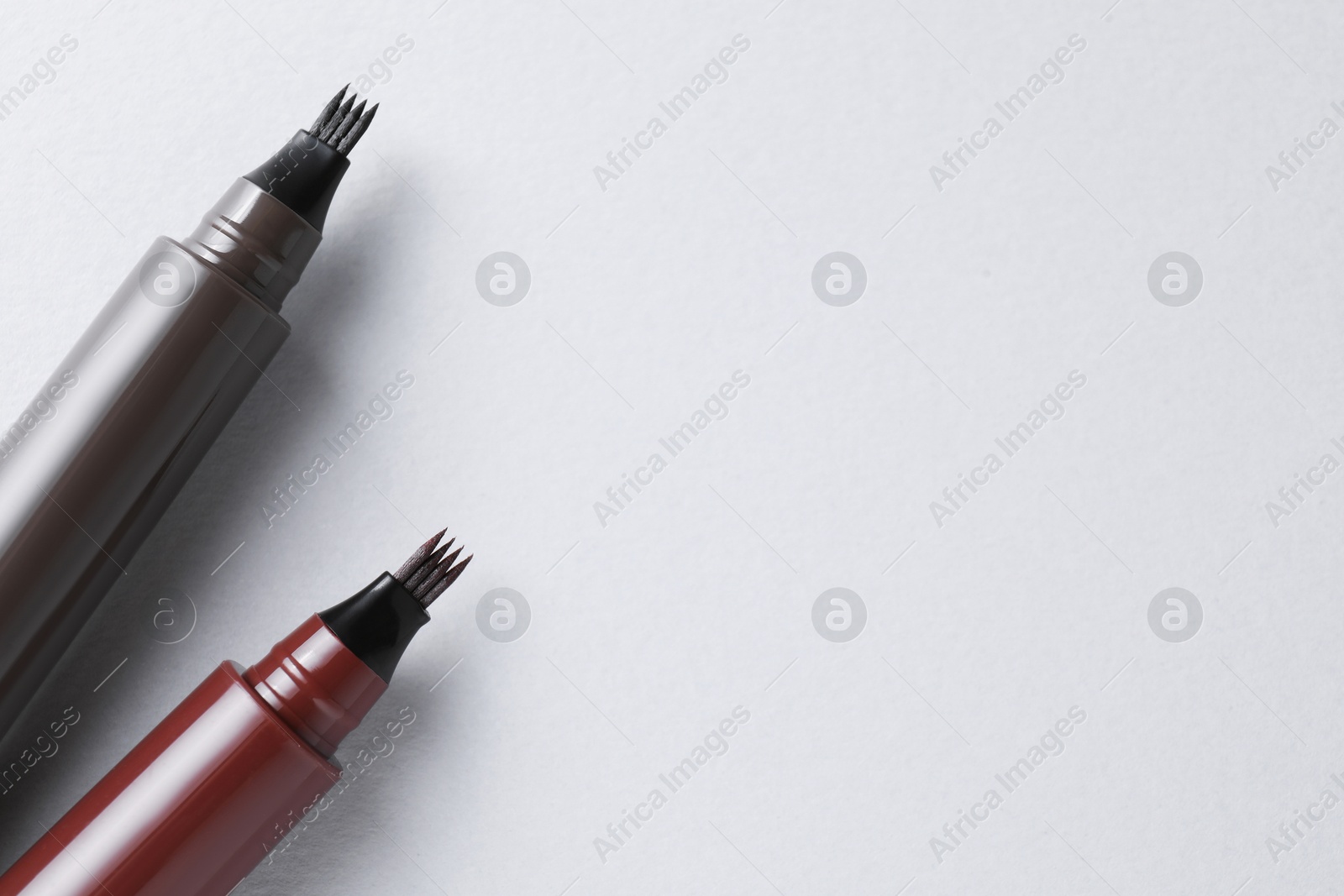 Liquid eyebrow pencils on white background, above view. Space for text Photo of Liquid eyebrow pencils on white background, above view. Space for text