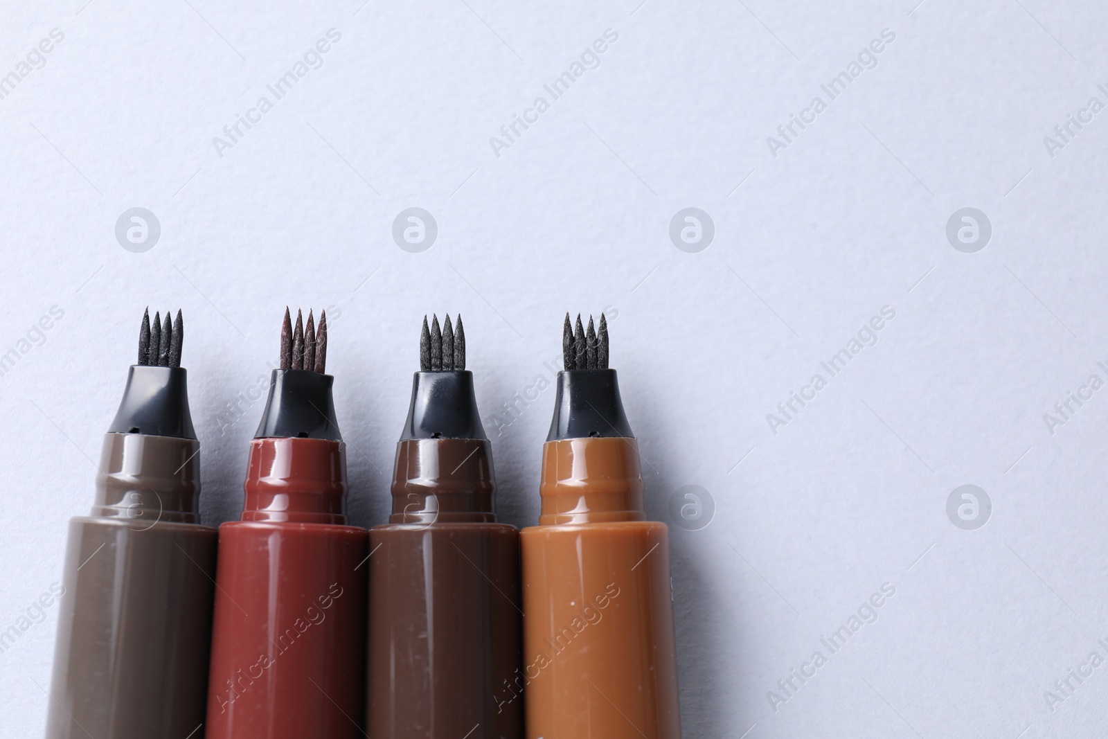 Liquid eyebrow pencils on white background, flat lay. Space for text Photo of Liquid eyebrow pencils on white background, flat lay. Space for text