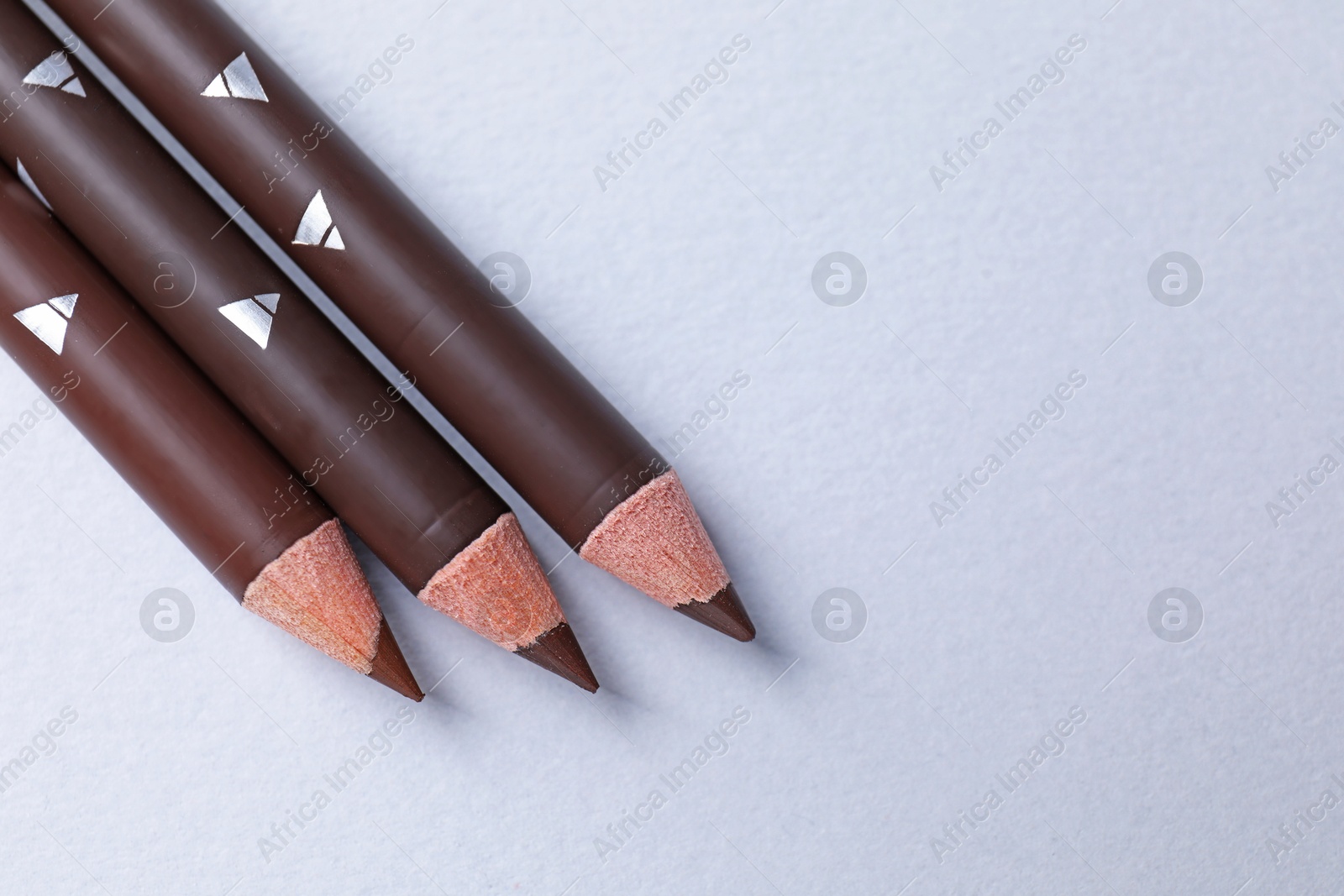 Three eyebrow pencils on white background, flat lay. Space for text Photo of Three eyebrow pencils on white background, flat lay. Space for text