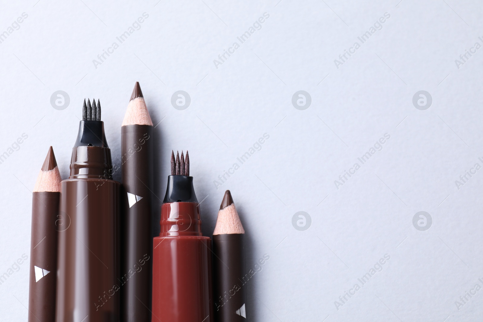 Different eyebrow pencils on white background, flat lay. Space for text Photo of Different eyebrow pencils on white background, flat lay. Space for text