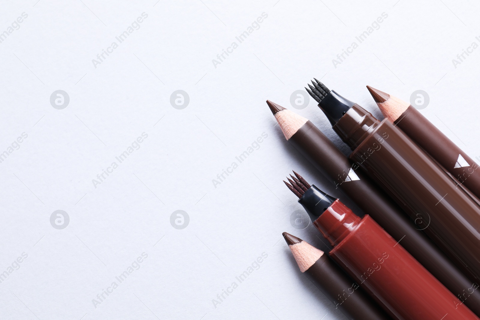 Different eyebrow pencils on white background, flat lay. Space for text Photo of Different eyebrow pencils on white background, flat lay. Space for text