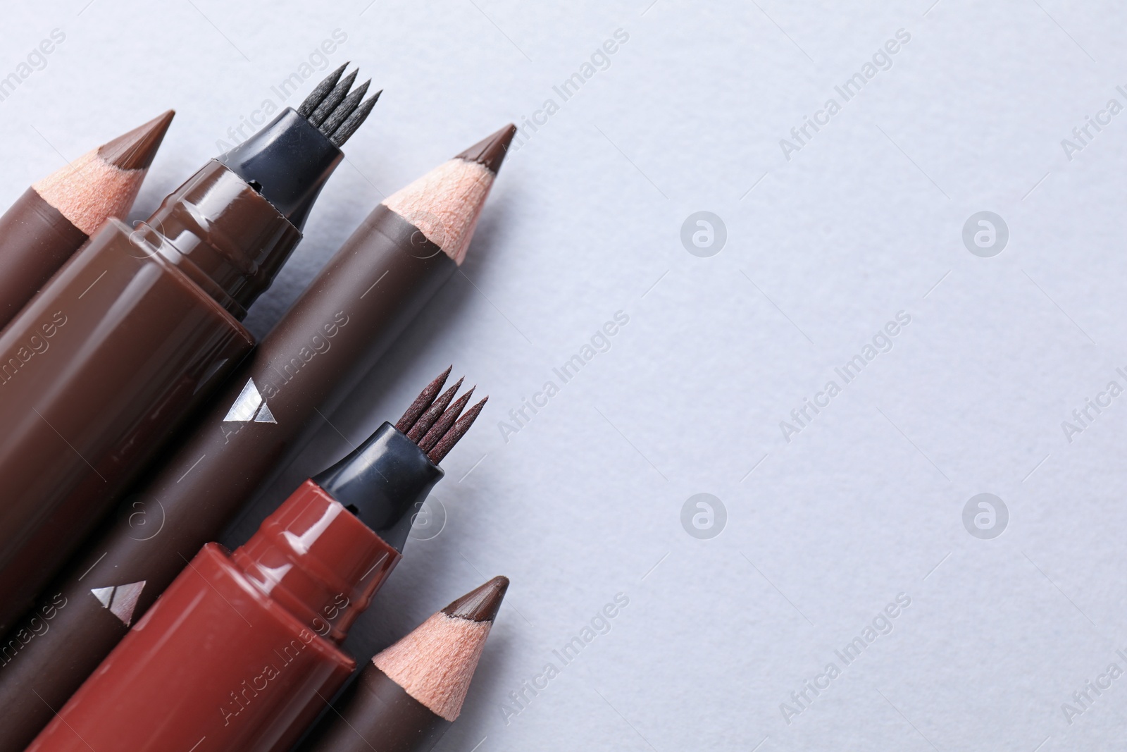 Different eyebrow pencils on white background, above view. Space for text Photo of Different eyebrow pencils on white background, above view. Space for text
