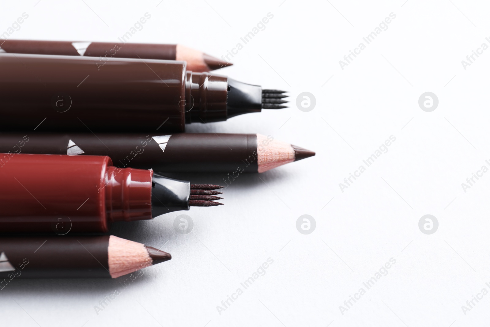 Different eyebrow pencils on white background, closeup. Space for text Photo of Different eyebrow pencils on white background, closeup. Space for text