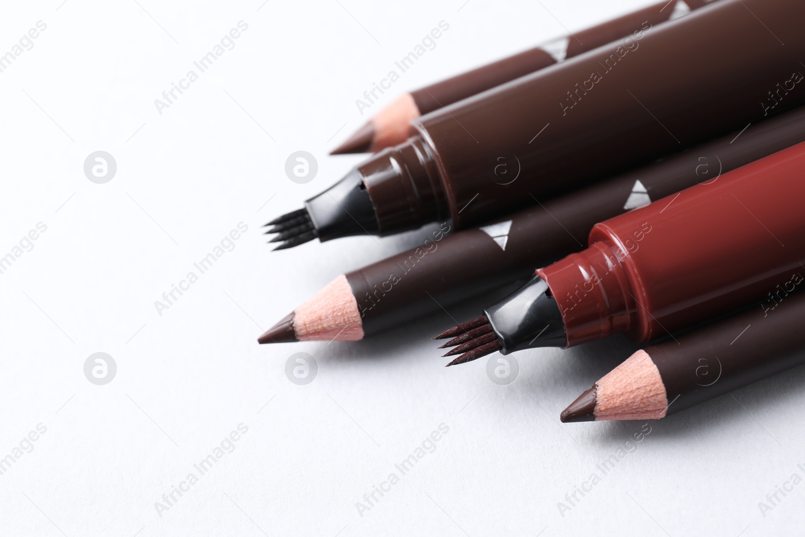 Different eyebrow pencils on white background, closeup. Space for text Photo of Different eyebrow pencils on white background, closeup. Space for text