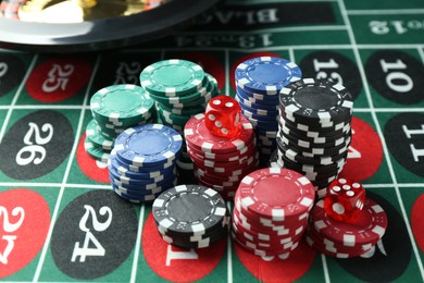 Photo of Casino chips and dice on roulette table, closeup