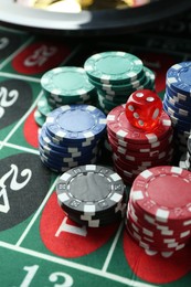 Photo of Casino chips and die on roulette table, closeup