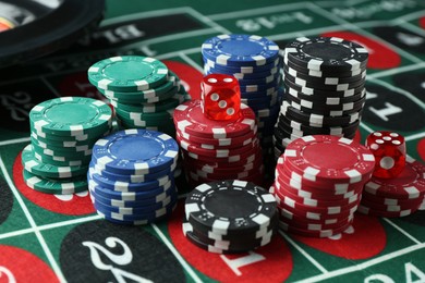 Photo of Casino chips and dice on roulette table, closeup