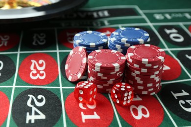 Photo of Casino chips and dice on roulette table, closeup