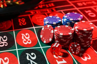 Photo of Casino chips and dice on roulette table, closeup
