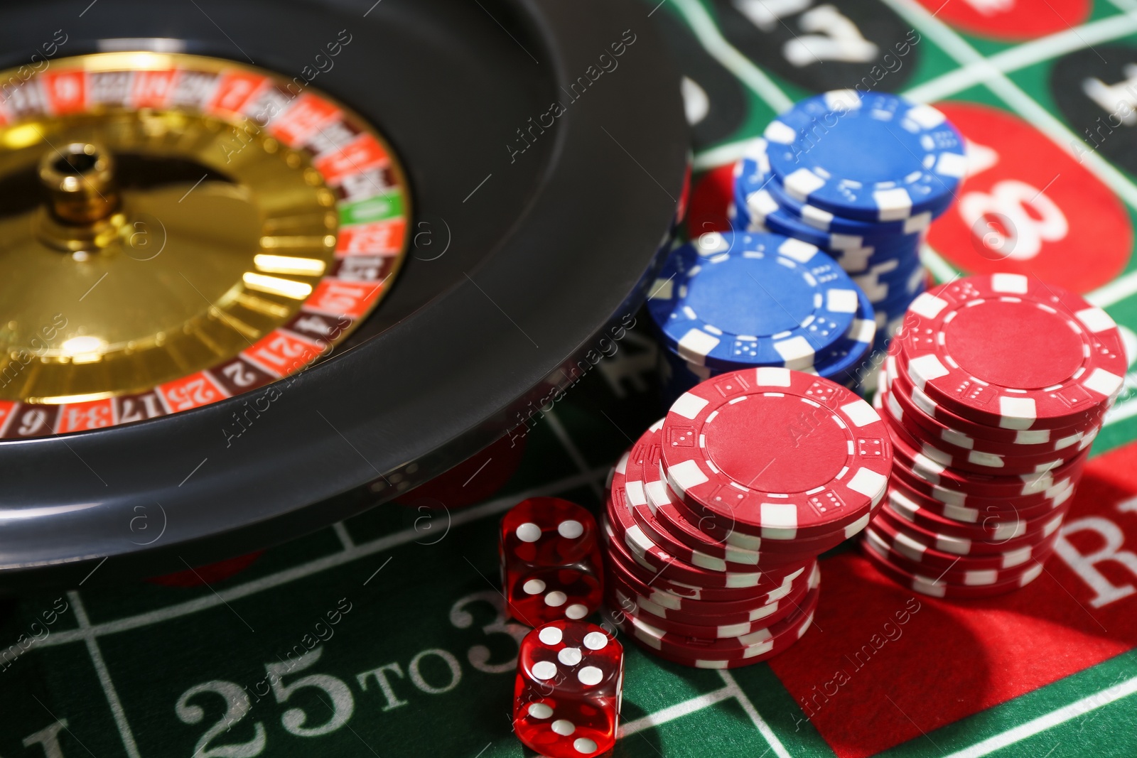 Photo of Casino chips, dice and roulette wheel on table, closeup
