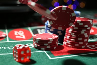 Photo of Casino chips and die falling on roulette table against blurred lights, closeup