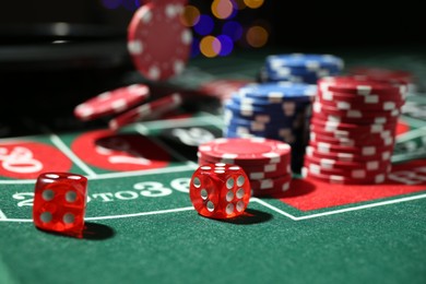 Photo of Casino chips and dice falling on roulette table against blurred lights, closeup