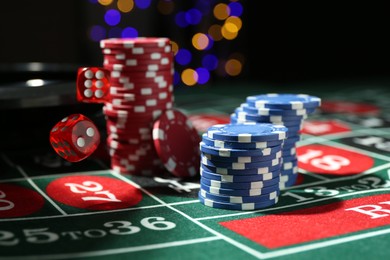 Photo of Casino chips and dice falling on roulette table against blurred lights, closeup