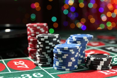 Photo of Casino chips on roulette table against blurred lights, closeup