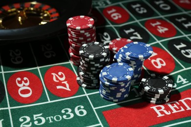 Photo of Casino chips and roulette wheel on table, closeup