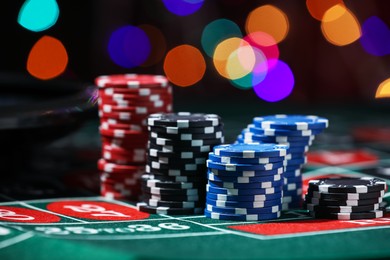 Photo of Casino chips on roulette table against blurred lights, closeup