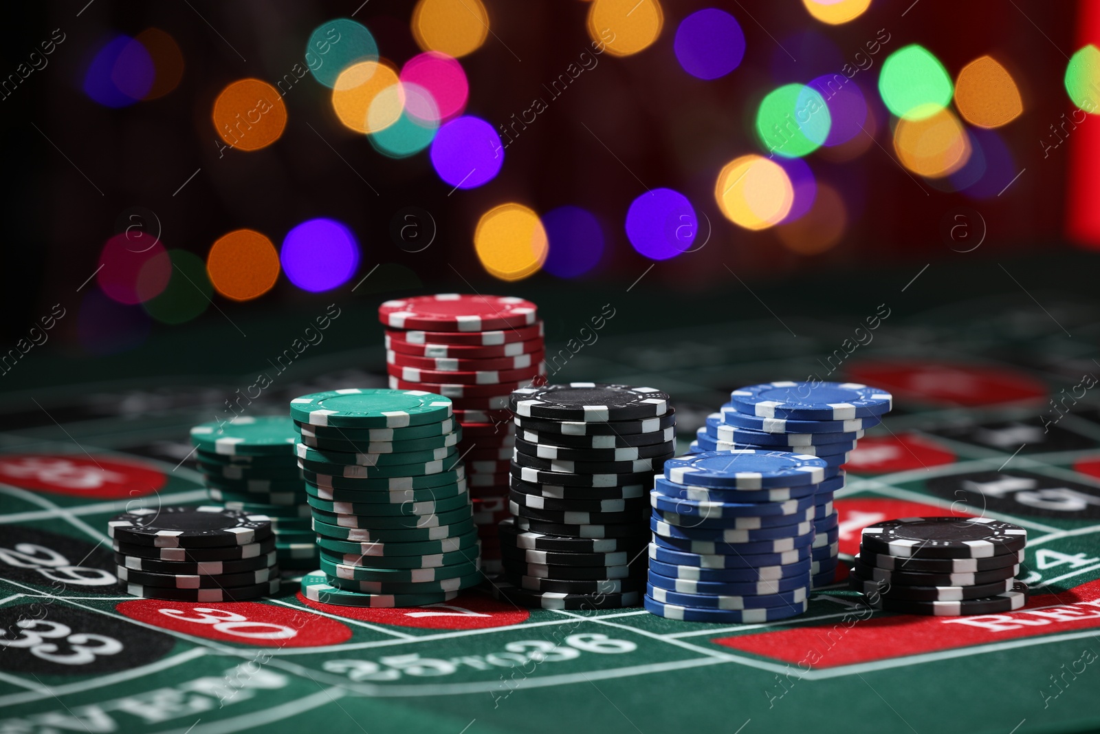 Photo of Casino chips on roulette table against blurred lights, closeup