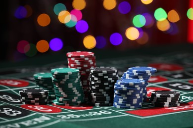 Photo of Casino chips on roulette table against blurred lights, closeup
