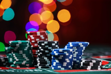 Photo of Casino chips on roulette table against blurred lights, closeup