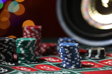 Photo of Casino chips on roulette table against blurred lights, closeup
