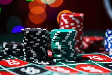 Photo of Casino chips on roulette table against blurred lights, closeup