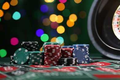Photo of Casino chips on roulette table against blurred lights, closeup