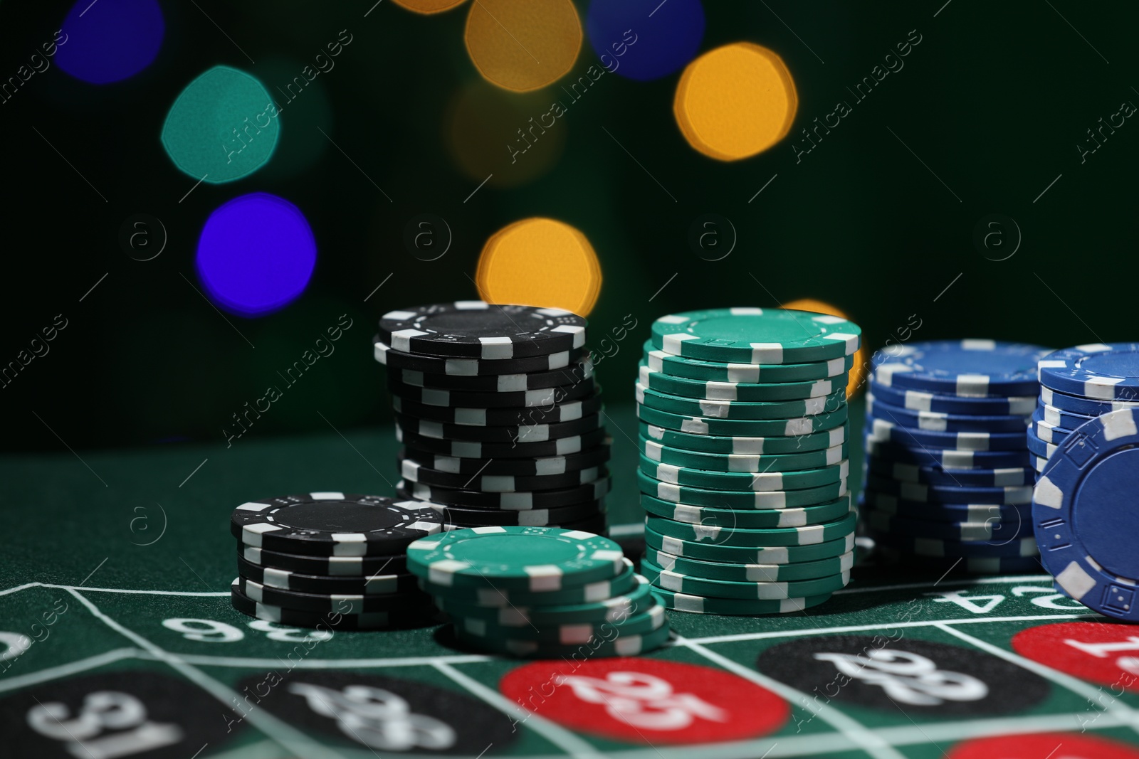 Photo of Casino chips on roulette table against blurred lights, closeup