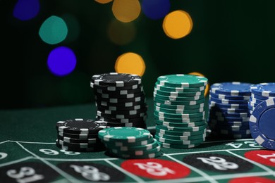 Photo of Casino chips on roulette table against blurred lights, closeup