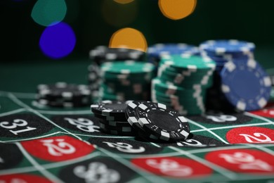 Photo of Casino chips on roulette table against blurred lights, closeup