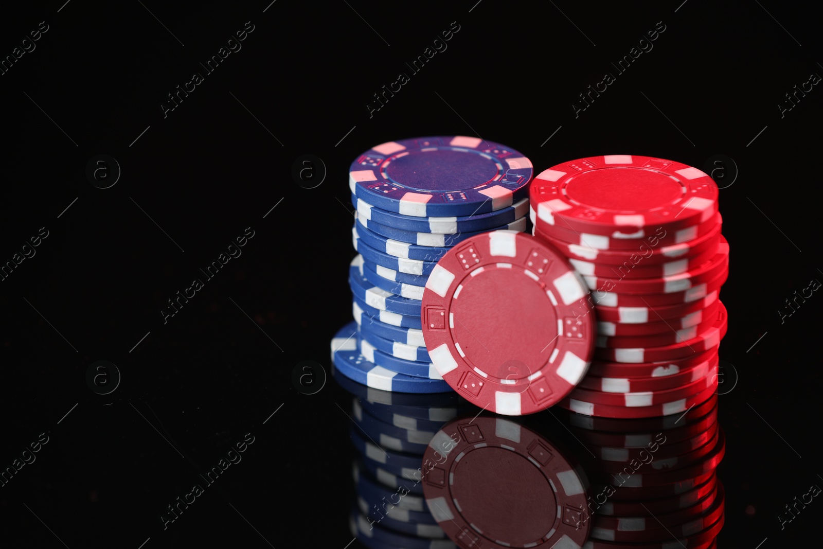 Casino chips on mirror surface against black background, closeup. Space for text Photo of Casino chips on mirror surface against black background, closeup. Space for text
