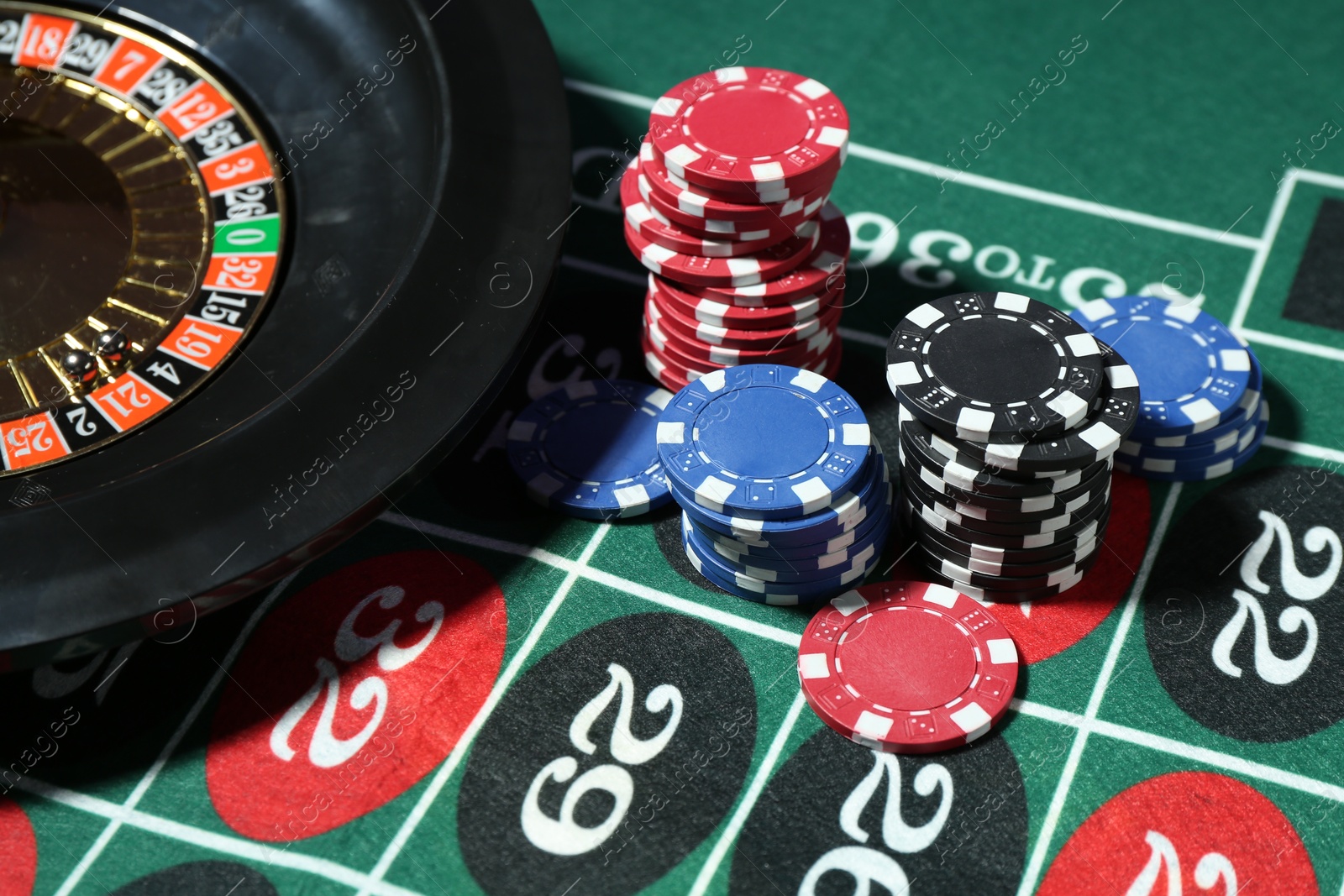 Casino chips and roulette wheel on table, closeup Photo of Casino chips and roulette wheel on table, closeup