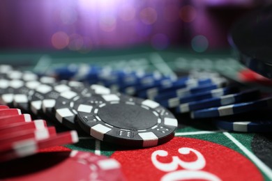 Photo of Casino chips on roulette table against blurred lights, closeup