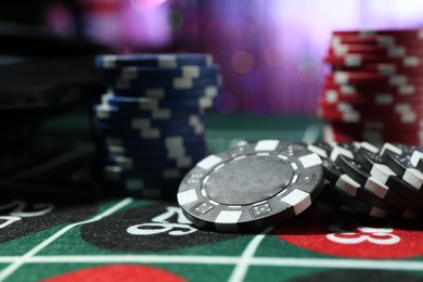 Photo of Casino chips on roulette table against blurred lights, closeup