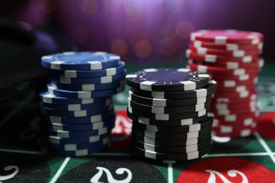 Photo of Casino chips on roulette table against blurred lights, closeup