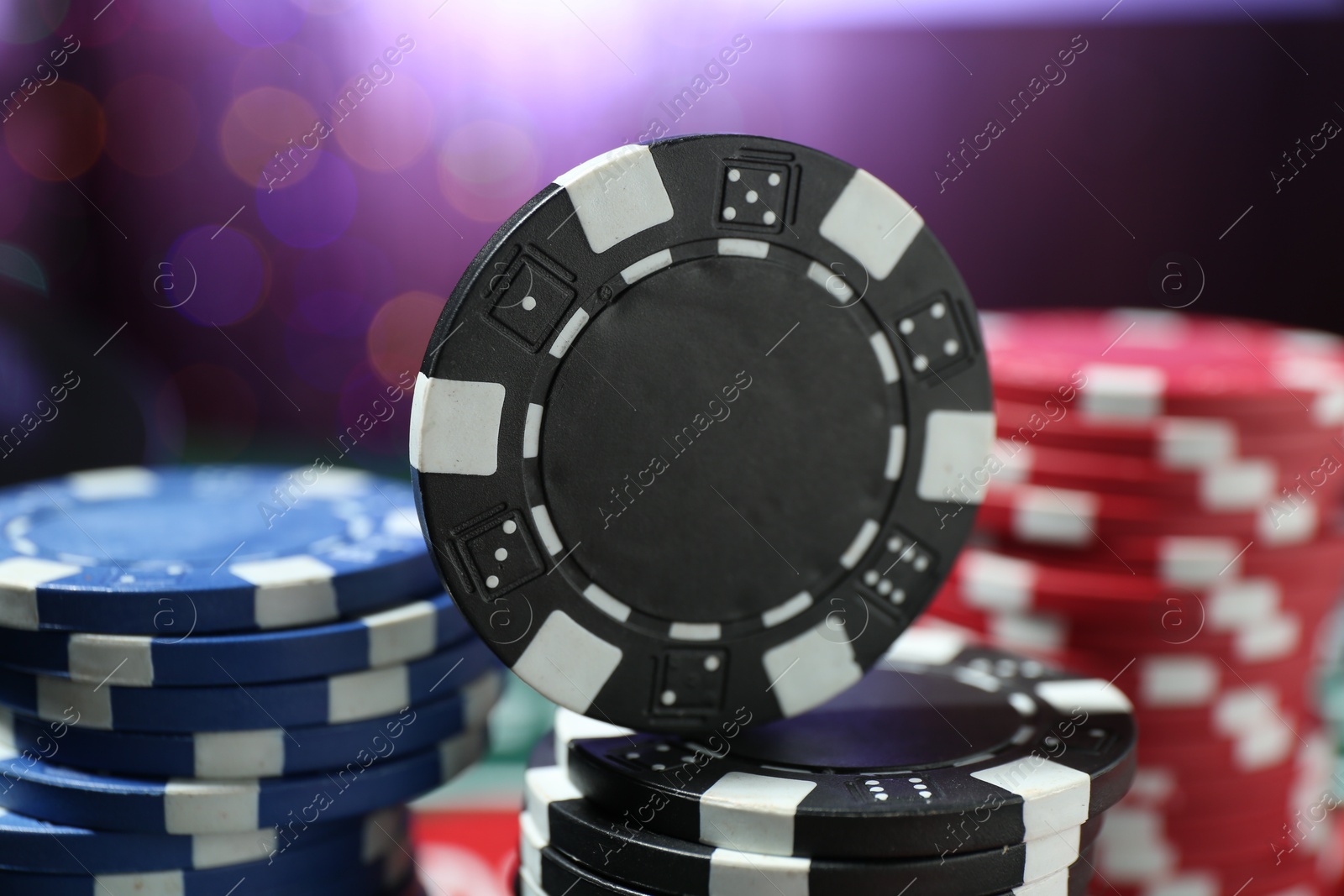 Casino chips against blurred lights, closeup view Photo of Casino chips against blurred lights, closeup view