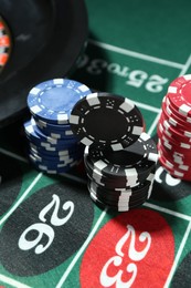 Photo of Casino chips and roulette wheel on table, closeup