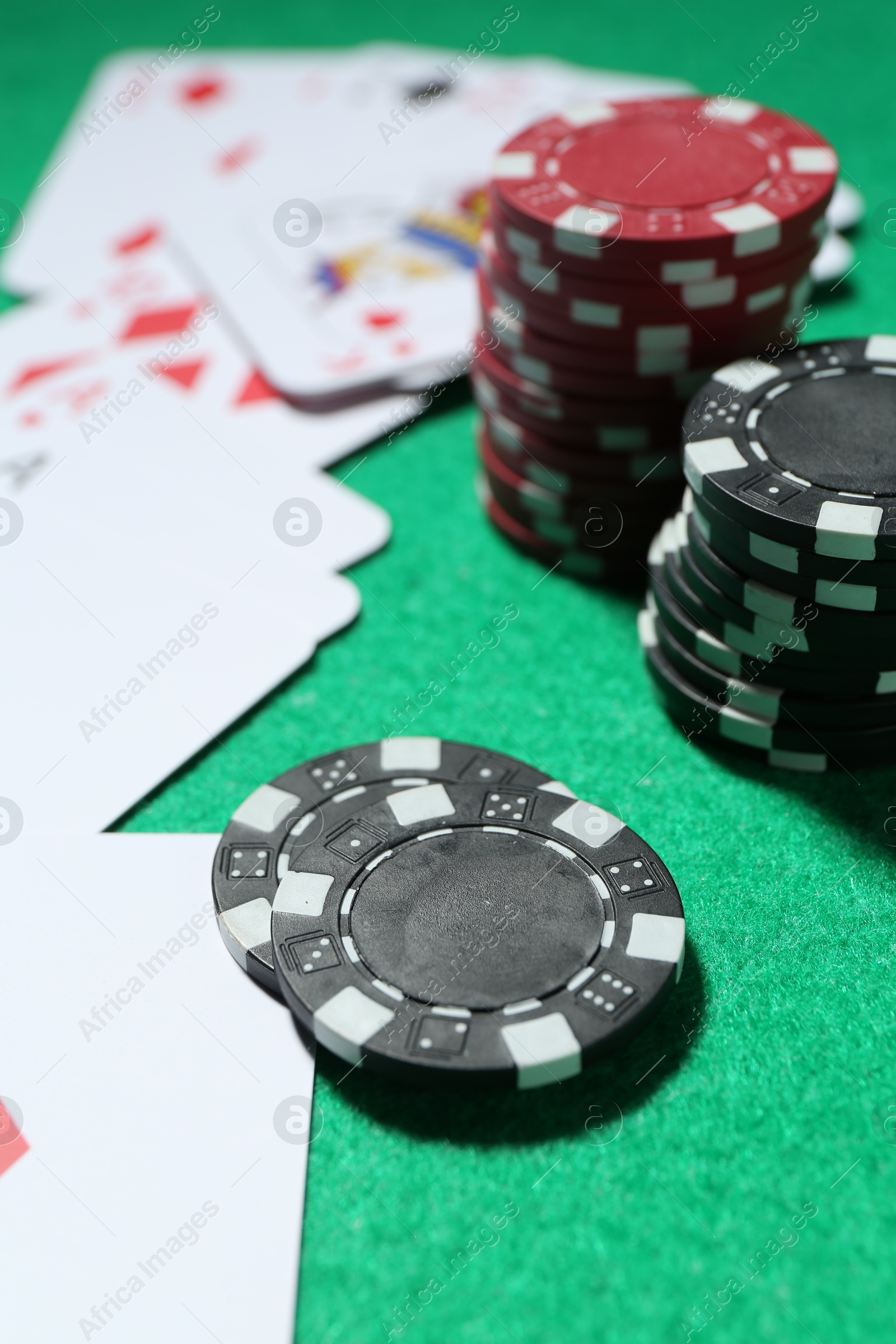 Casino chips and playing cards on green table, closeup Photo of Casino chips and playing cards on green table, closeup
