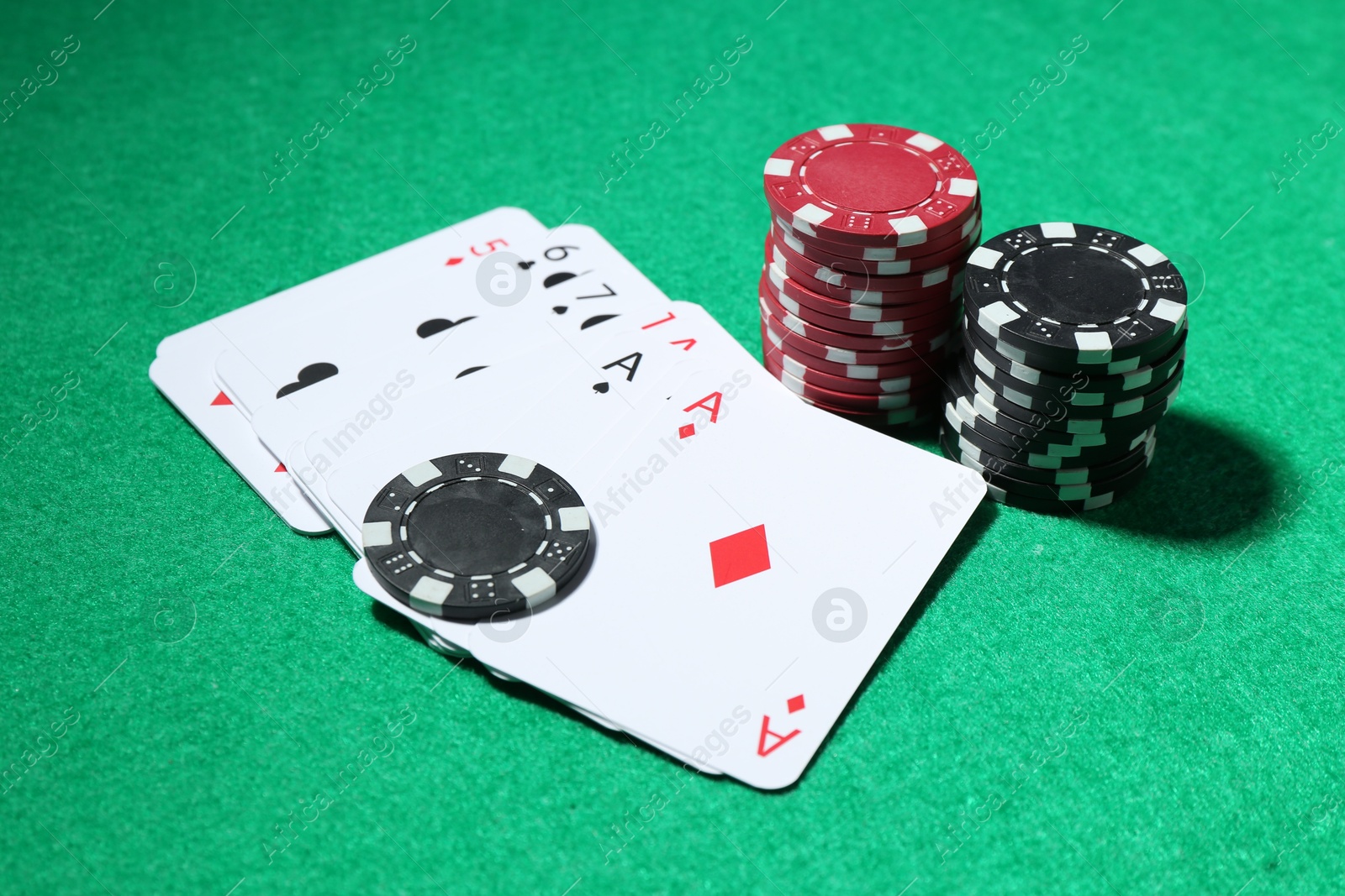 Casino chips and playing cards on green table, closeup Photo of Casino chips and playing cards on green table, closeup