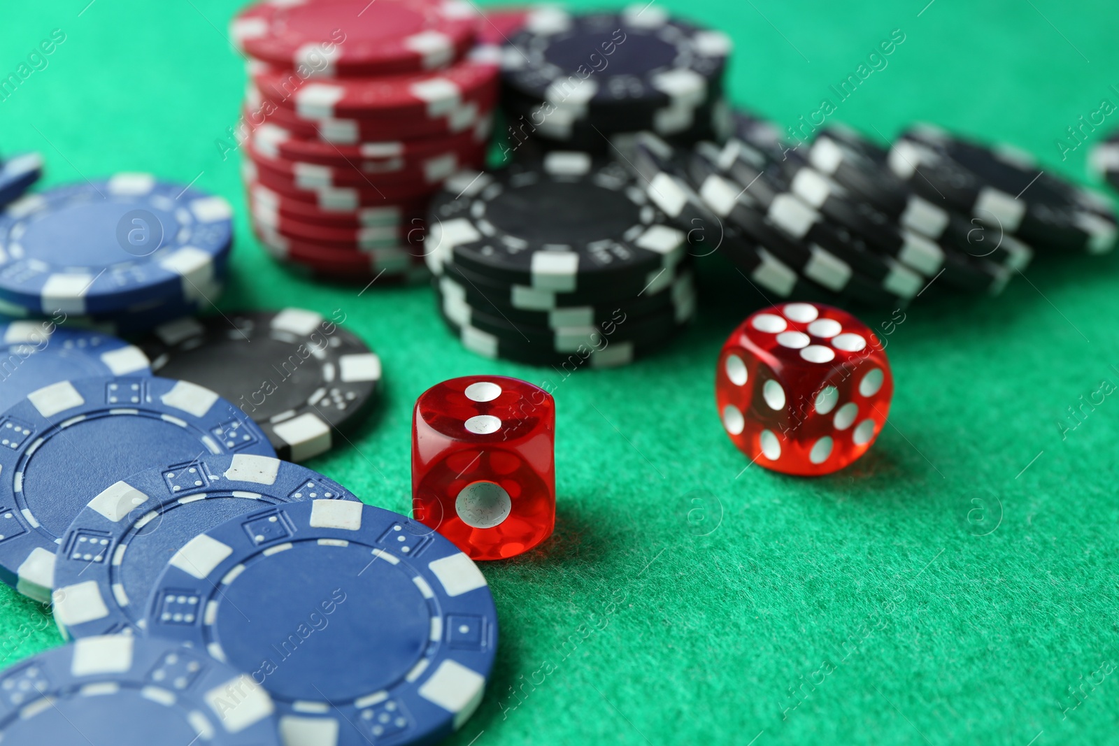 Photo of Casino chips and dice on green table, closeup