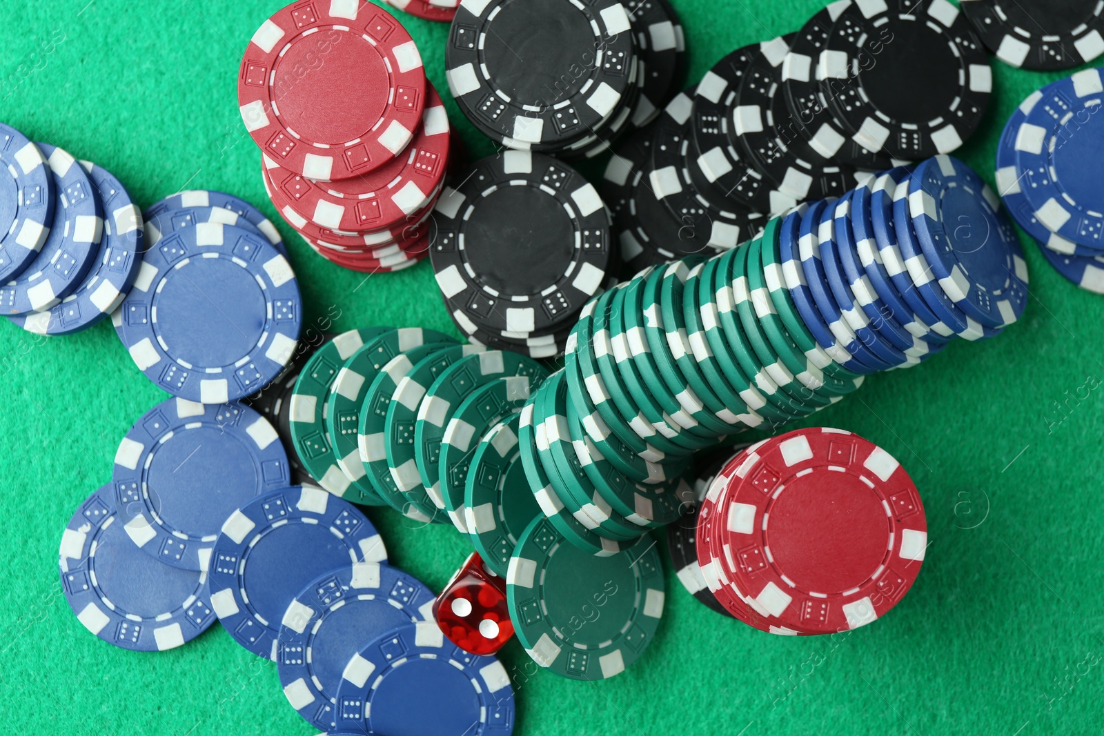 Casino chips and die on green table, flat lay Photo of Casino chips and die on green table, flat lay