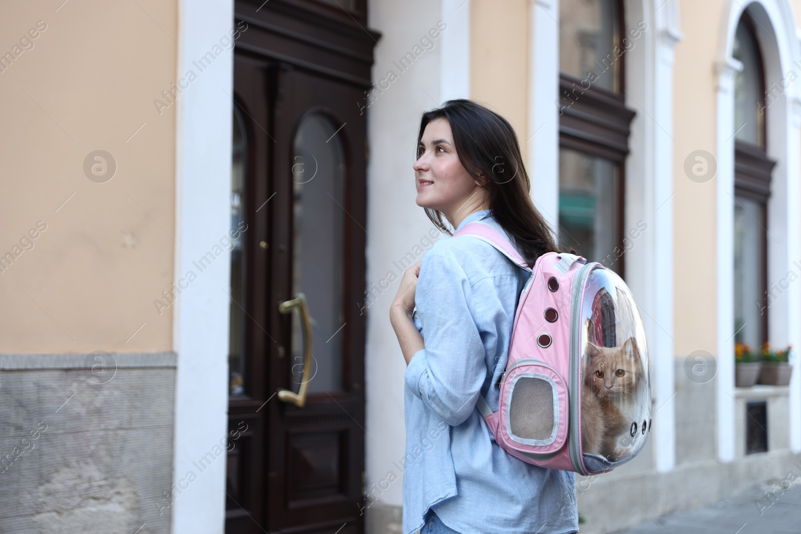 Woman with her cute cat in backpack carrier on city street. Space for text Photo of Woman with her cute cat in backpack carrier on city street. Space for text