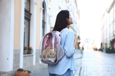 Photo of Woman with her cute cat in backpack carrier on city street