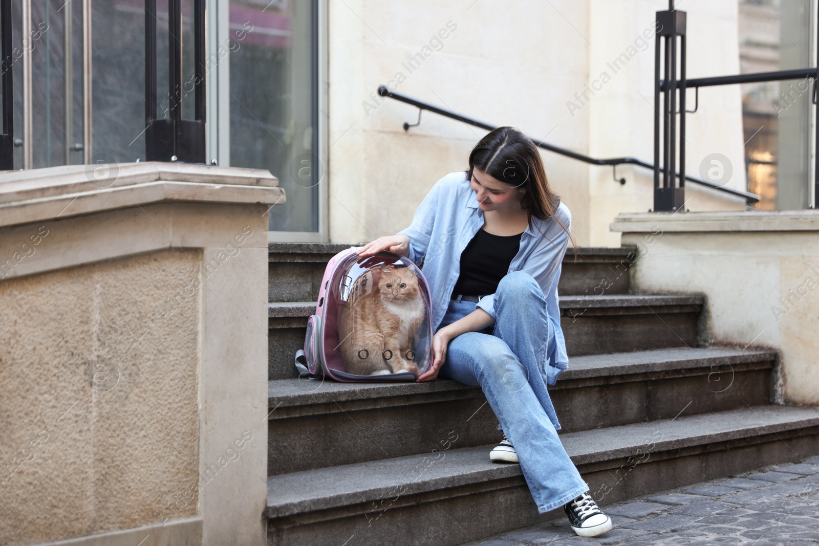 Woman with her cute cat in backpack carrier on stairs outdoors Photo of Woman with her cute cat in backpack carrier on stairs outdoors