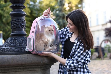 Photo of Woman with her cute cat in backpack carrier on city street