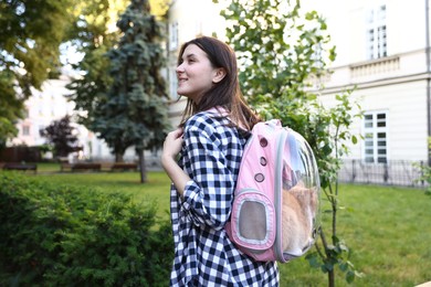 Photo of Woman with her cute cat in backpack carrier at park
